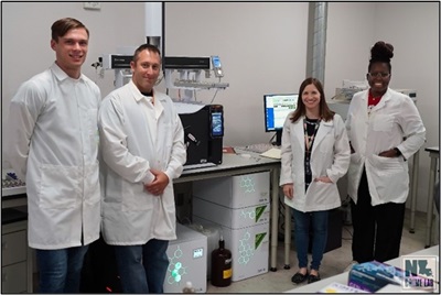 Image of four people in white lab coats standing in a lab