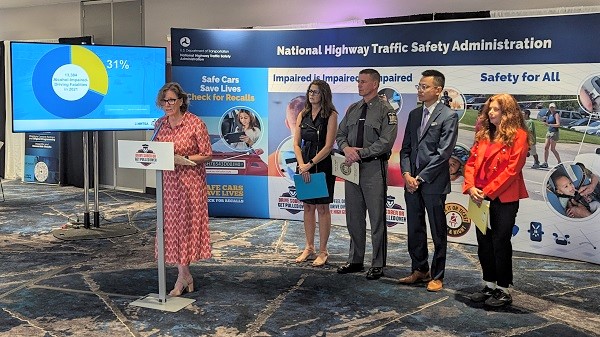 Highway safety officials stand together behind a podium for a press conference