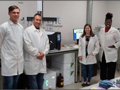 Image of four people in white lab coats standing in a lab
