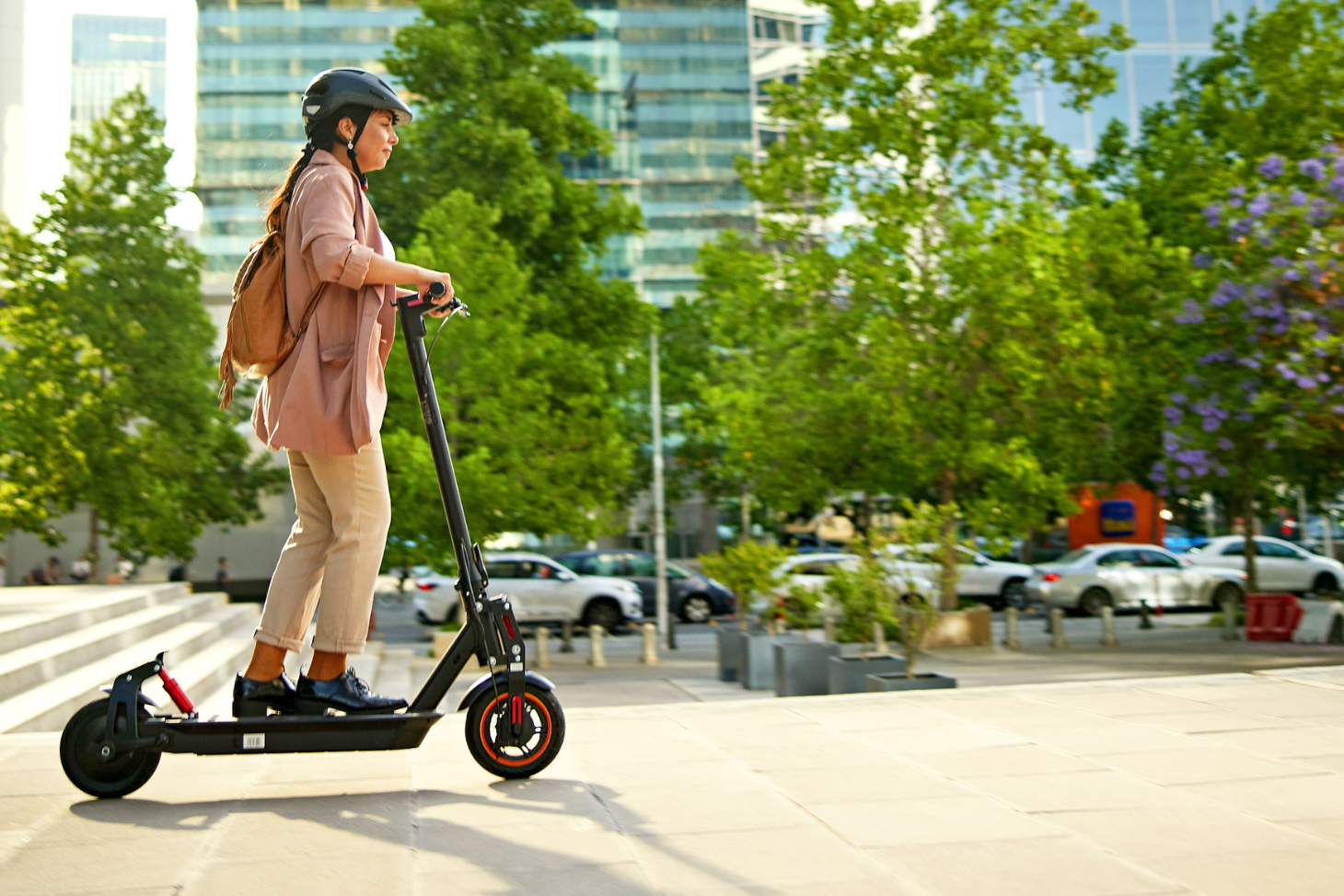Woman wearing a helmet riding an electric scooter on the sidewalk