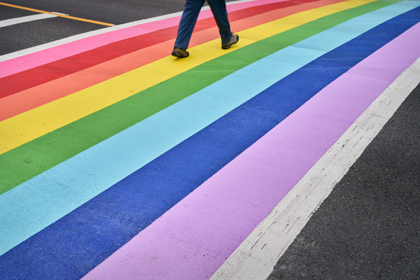 View of a person crossing the street on a rainbow crosswalk