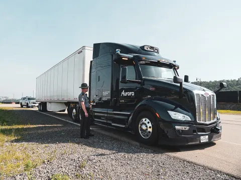 A police officer standing beside a semi truck on the side of the road